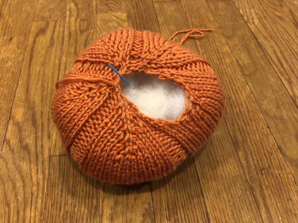 a knitted pumpkin with a large opening, showing that it is full of stuffing