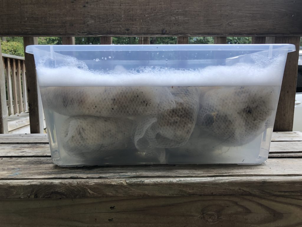 a clear, plastic tub full of warm, soapy water and garment bags full of fleece