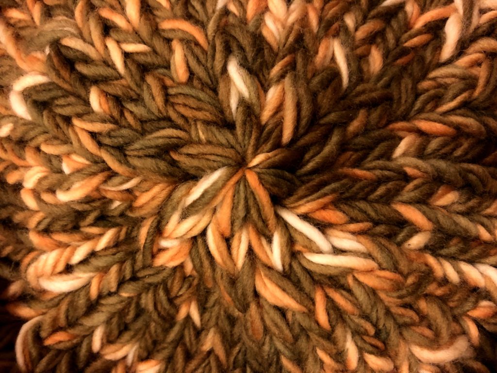 the bottom of a knitting bag, held up so that the starburst pattern in the center is visible