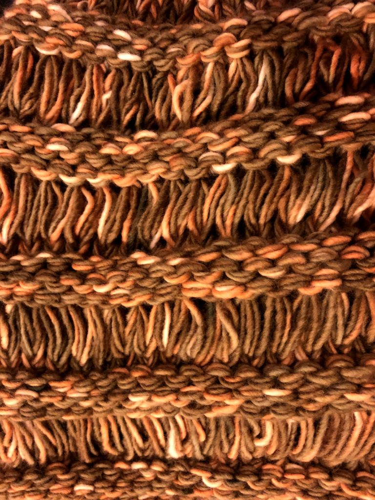 a close-up of the knitted bag's texture, showing alternating horizontal bumps and vertical gaps