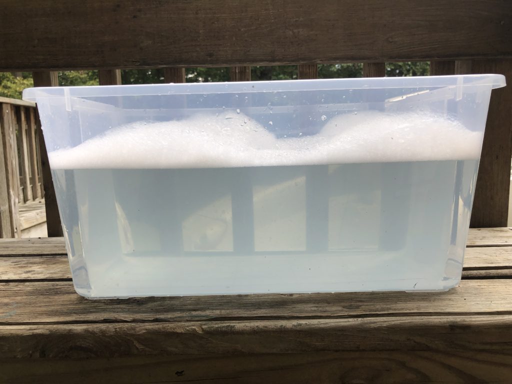 a clear, plastic tub full of warm, soapy water
