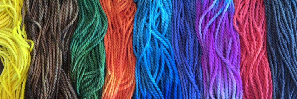 several hanks of hand-dyed yarn arranged side by side and lying vertically