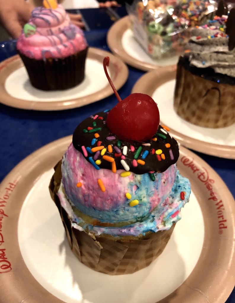 several decadent cupcakes, including one shaped like a scoop of ice cream with hot fudge and a cherry