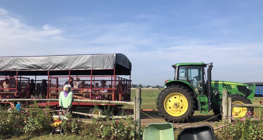 a tractor pulling a covered wagon full of hay bales and children