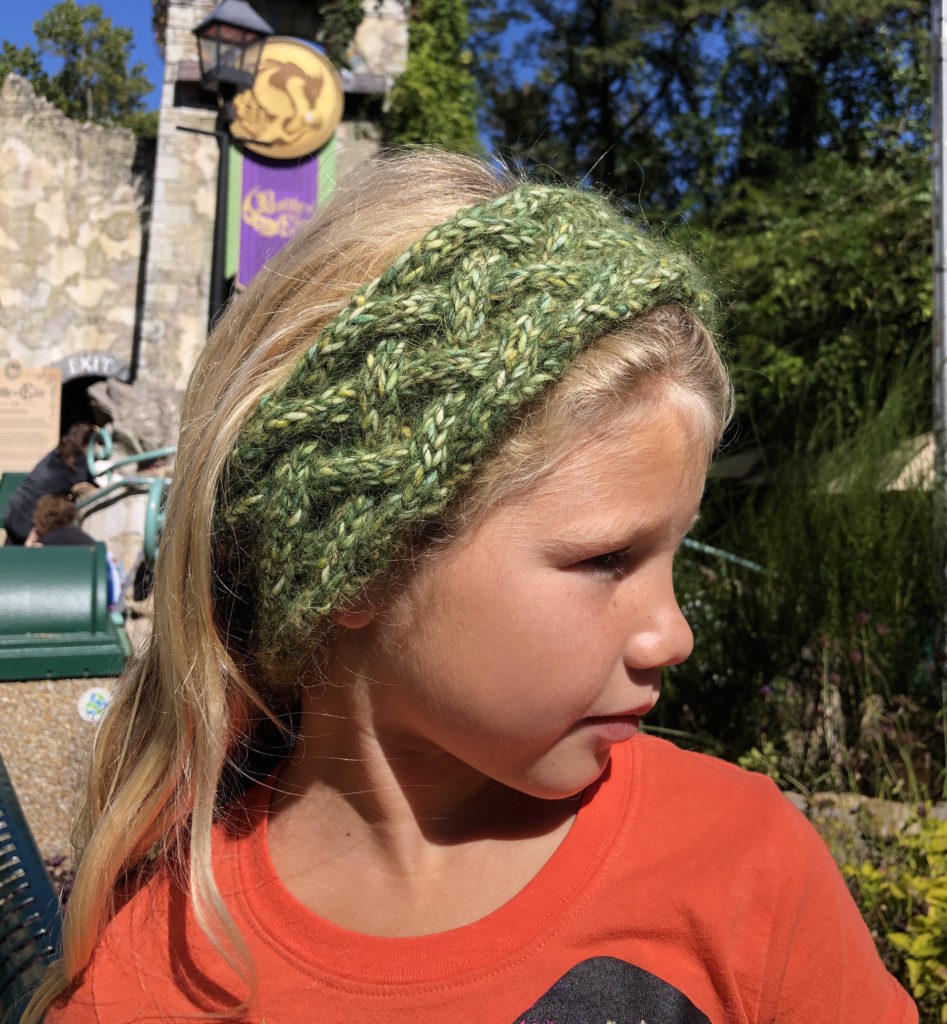 a young girl wearing a knitted braided cabled headband