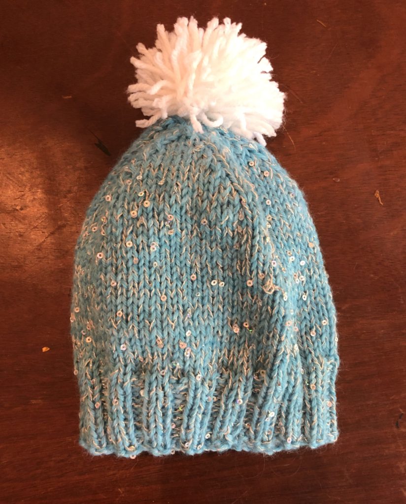 a knitted cap with sequins and a fluffy pompom