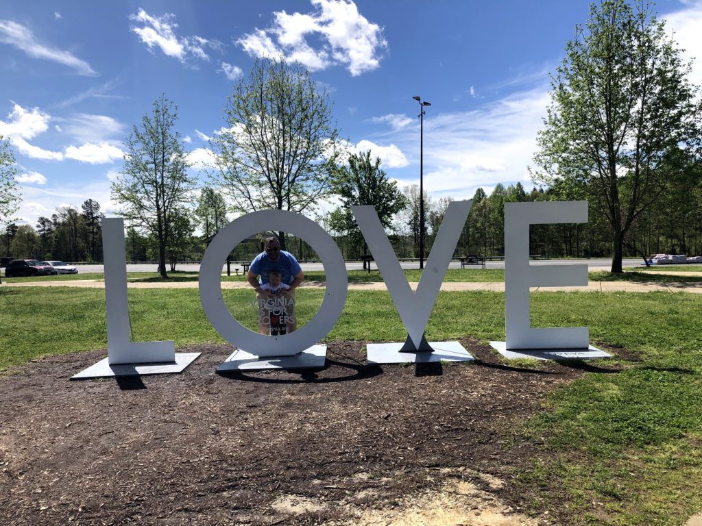 a father and son pose in the "O" of the LOVEworks at East Coast Gateway Welcome Center in New Kent, Virginia
