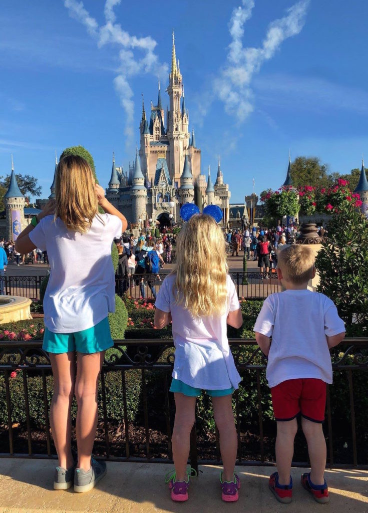 three children pause at the end of Main Street USA to look at Cinderella's Castle