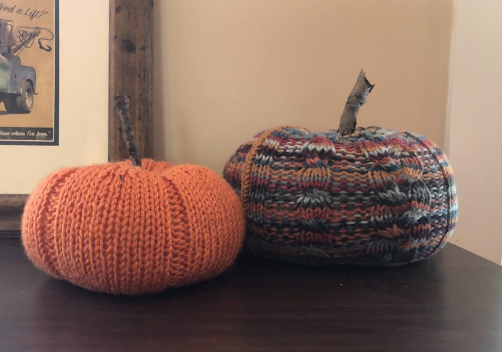 two knitted pumpkins on a tabletop