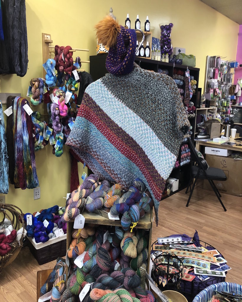 a knitted shawl atop a yarn display