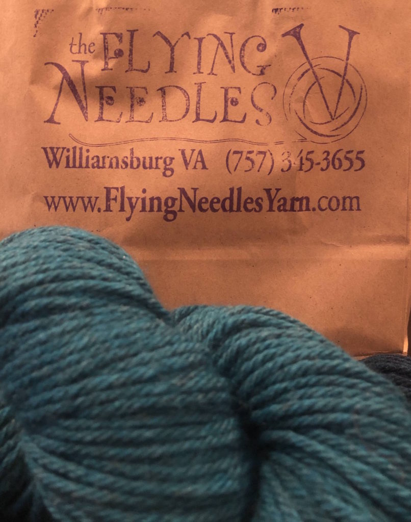 a bag with The Flying Needles logo and skein of yarn