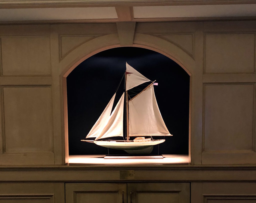 a model sailboat on a recessed shelf at the end of a hallway
