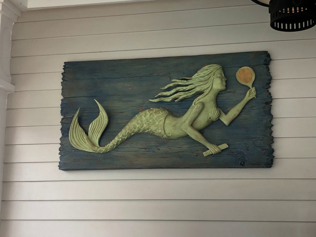 a carved mermaid adorns a piece of driftwood