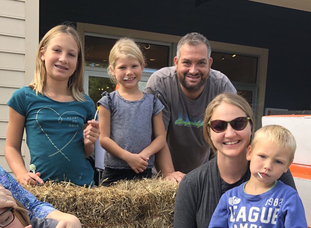 a smiling family of five with hay bales