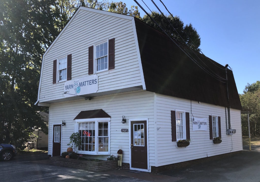 Yarn Matters local yarn shop exterior, a barn-type building with a bay window and an OPEN sign