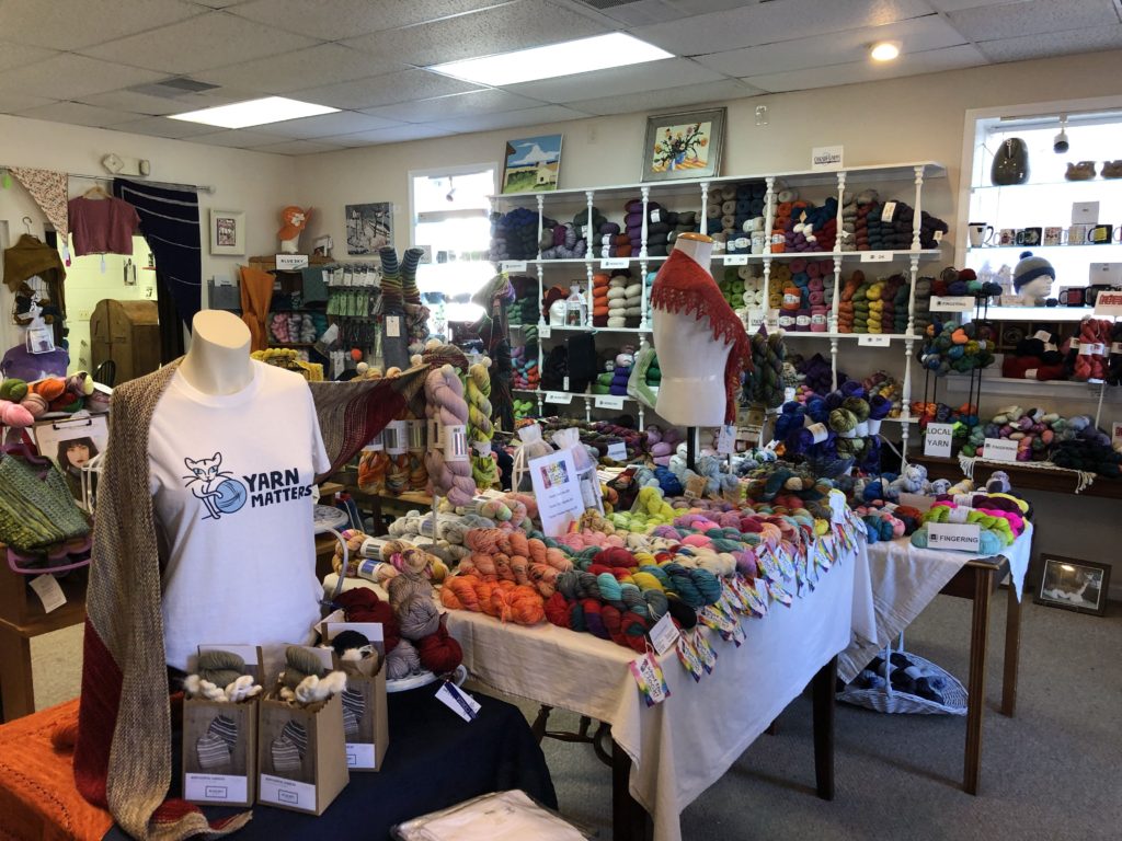 a room full of yarn piled on tables and filling shelves