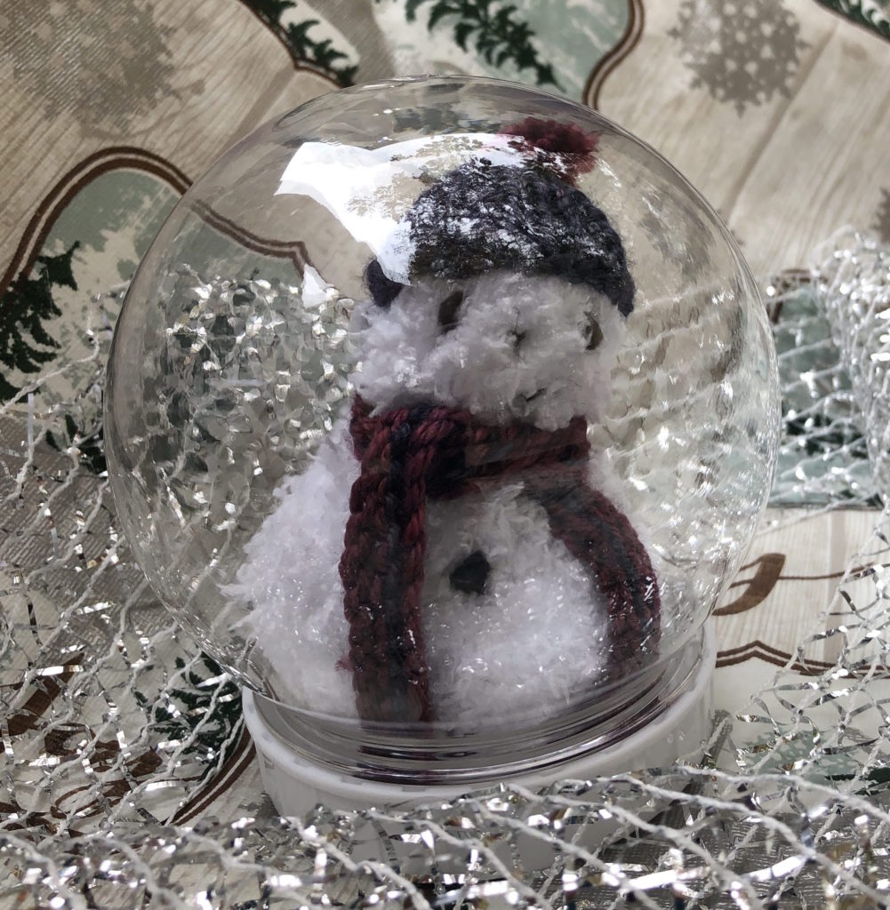 knitted snowman in snow globe