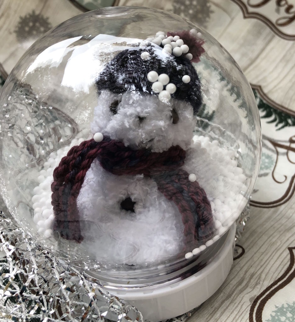 knitted snowman in snow globe