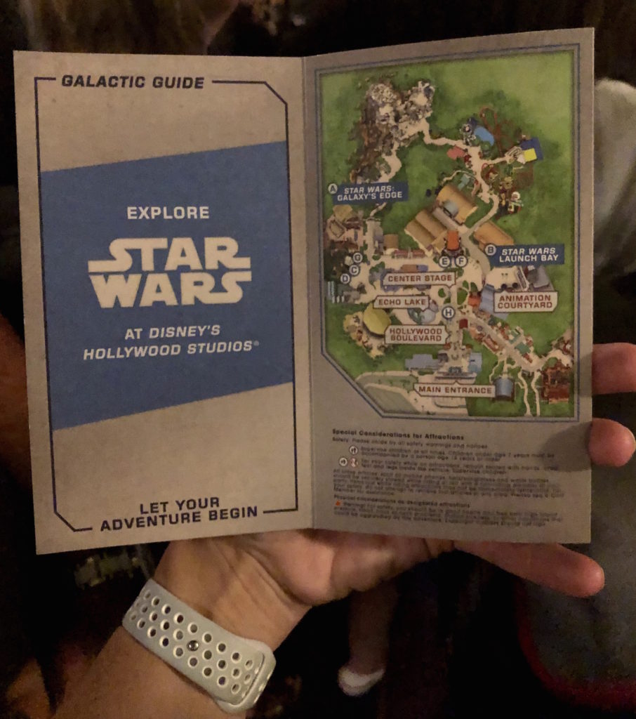 A pamphlet with a park map reads "Galactic Guide: Explore Star Wars at Disney's Hollywood Studios. Let your adventure begin."