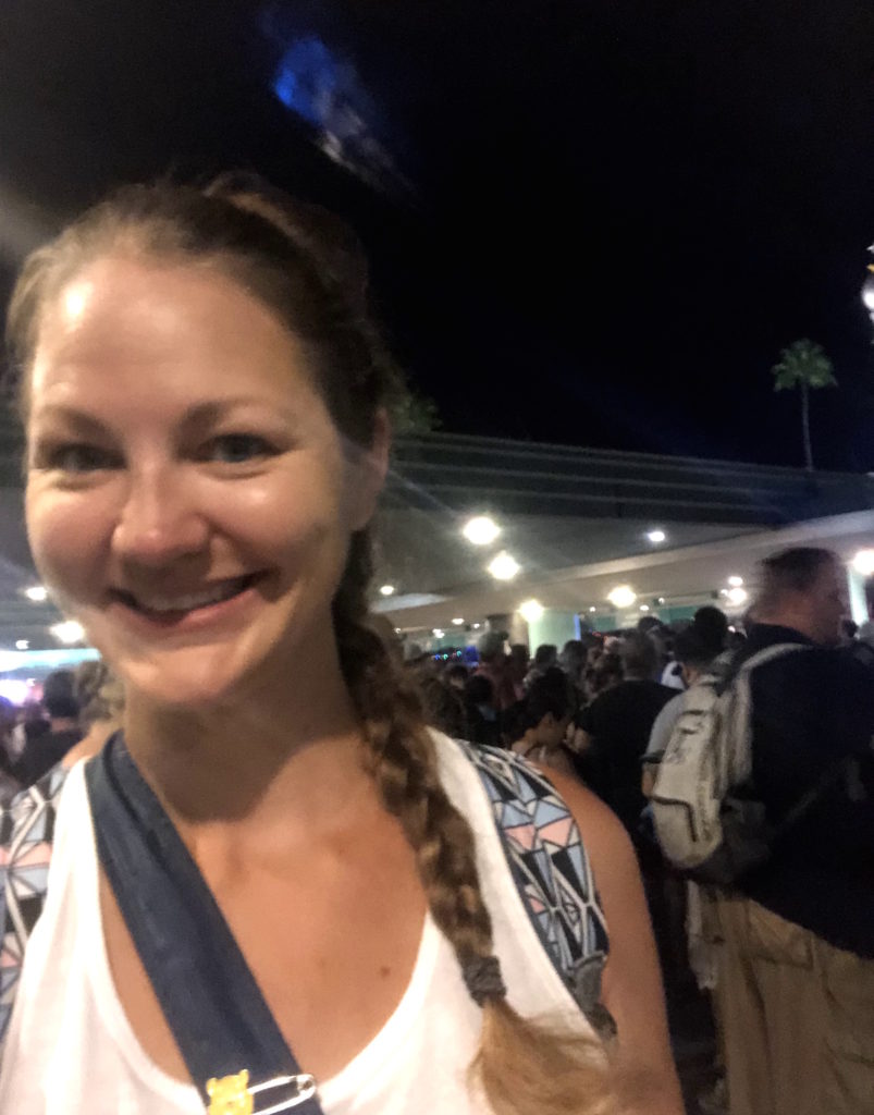 a woman with Princess Leia-styled hair smiles in front of a crowd waiting to enter Hollywood Studios