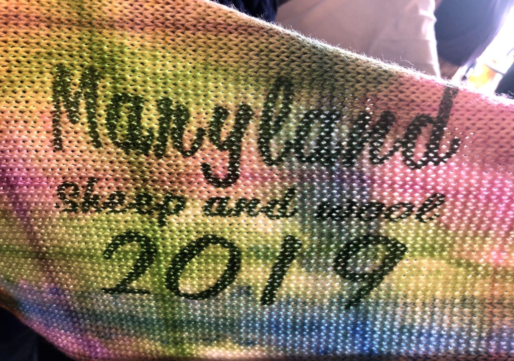 a knitted sock blank dyed pink, green, and blue reads "Maryland Sheep and Wool 2019"