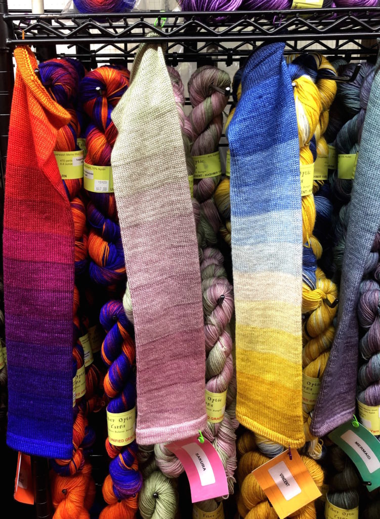 gradient sock blanks hang in front of colorful skeins of yarn