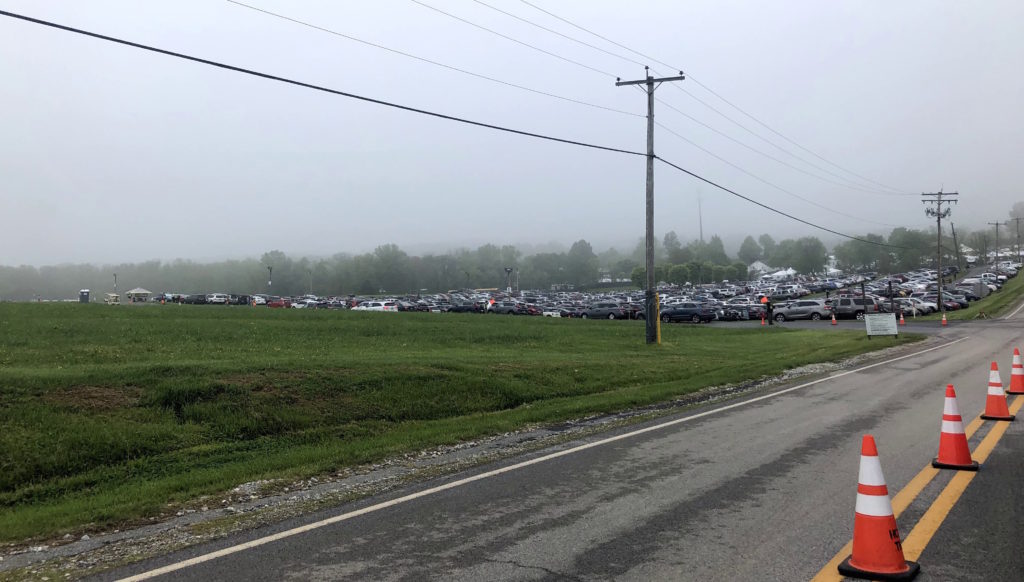 cones line the entrance to a crowded field that serves as a parking lot