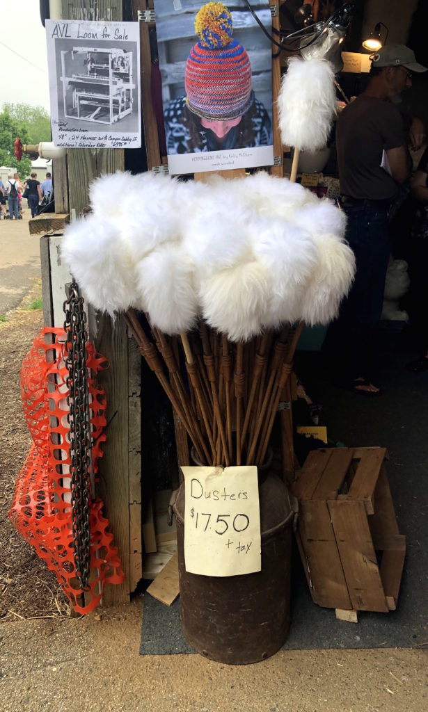 a large, antique milk jug of wool feather dusters flanks the entrance to a barn