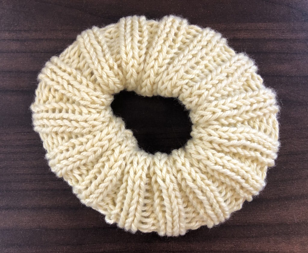 a ridged knitted scrunchie on a wood panel background