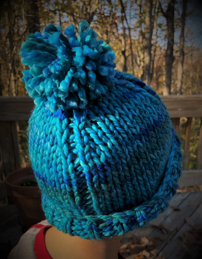 a vibrant multi-color blue knitted hat with pompom on a baby boy's head
