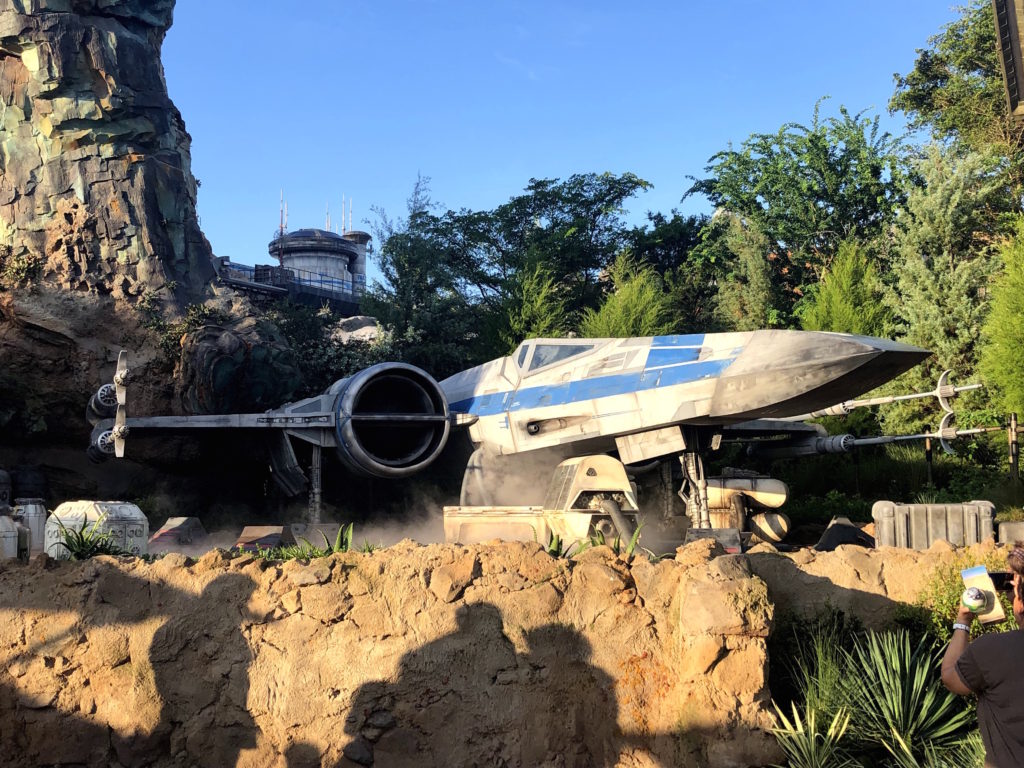 an x-wing starfighter is parked on rocks outside of Batuu