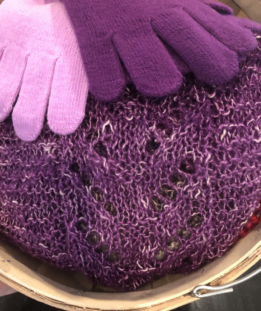a closeup of the lacework in the mulberry shawl, flanked by two pairs of matching gloves