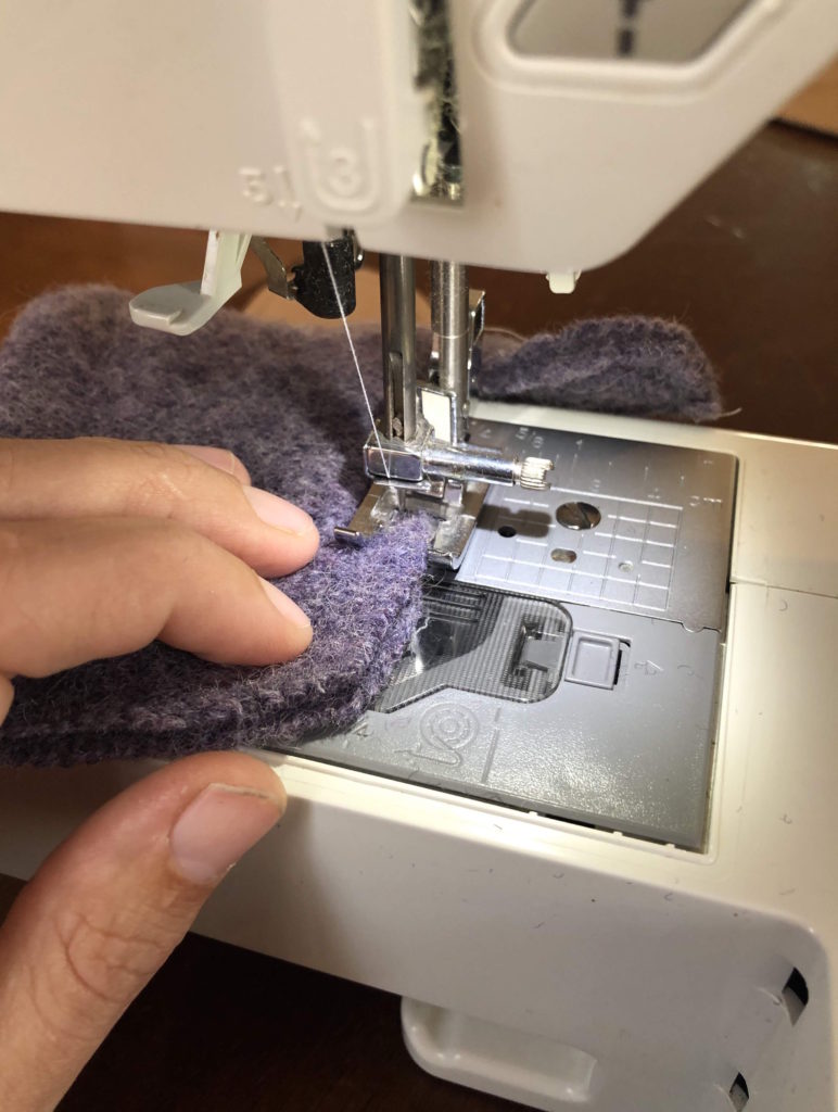 a close-up view of two pieces of woolen mitten being sewn together