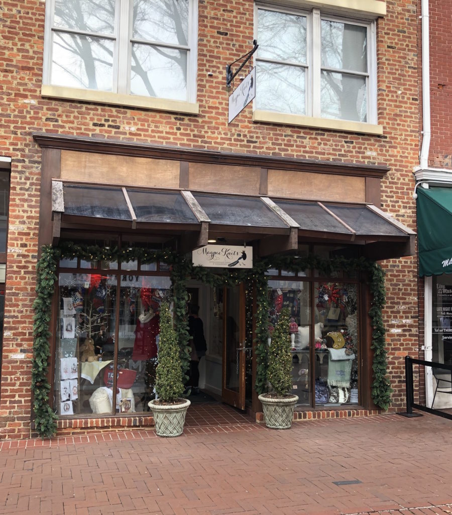 the exterior of Magpie Knits is flanked with two potted Christmas trees