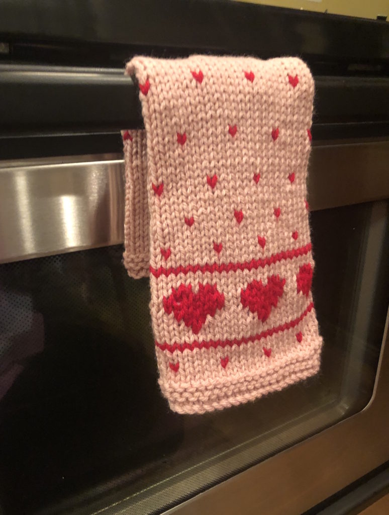 a towel decorated with hearts hangs on an oven handle