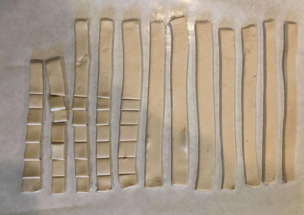 air dry-clay in strips being cut into squares
