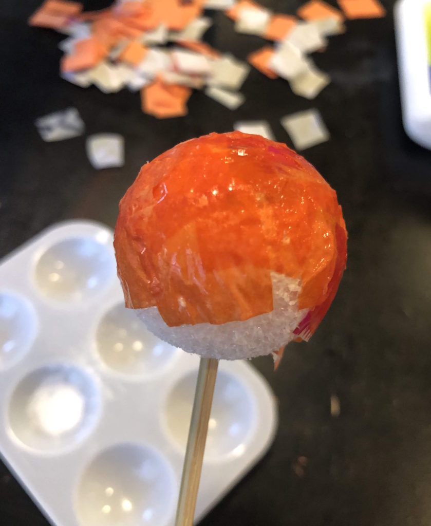 a decoupaged foam ball on a dowel rod