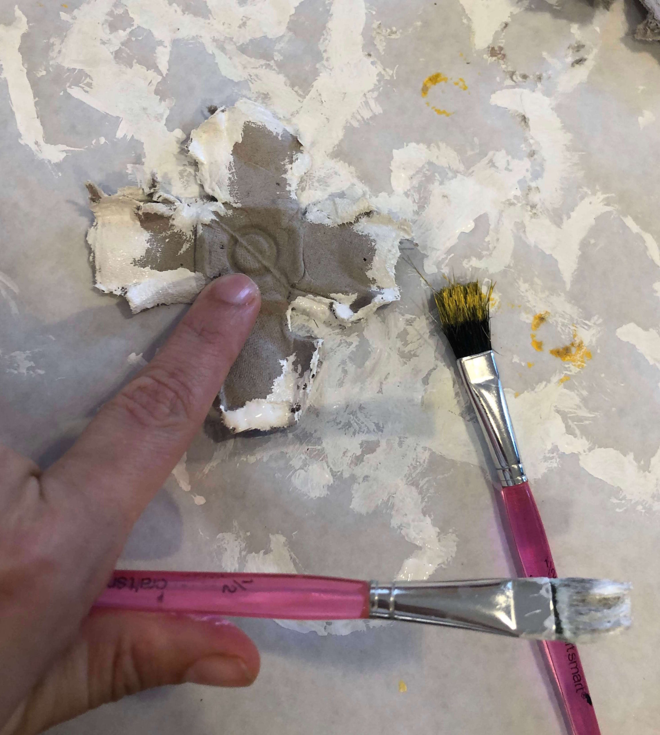 hold down the back of the egg carton flower with your finger while painting the edges of the petals