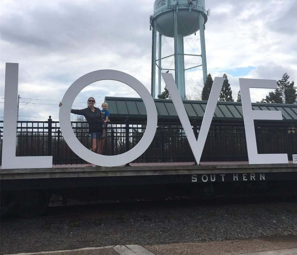 a mother and child pose on the LOVEworks in Old Town Manassas, Virginia
