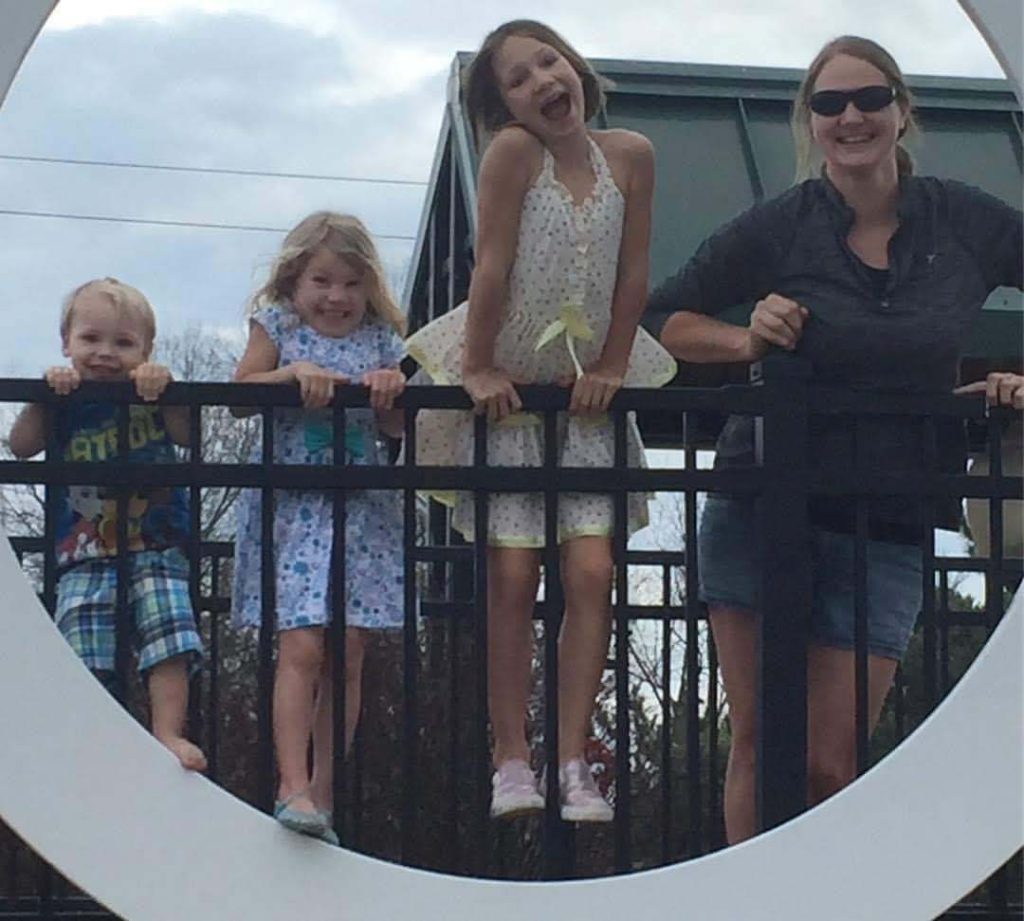 a mother and three children pose on the LOVEworks by the Harris Pavilion in Old Town Manassas, Virginia