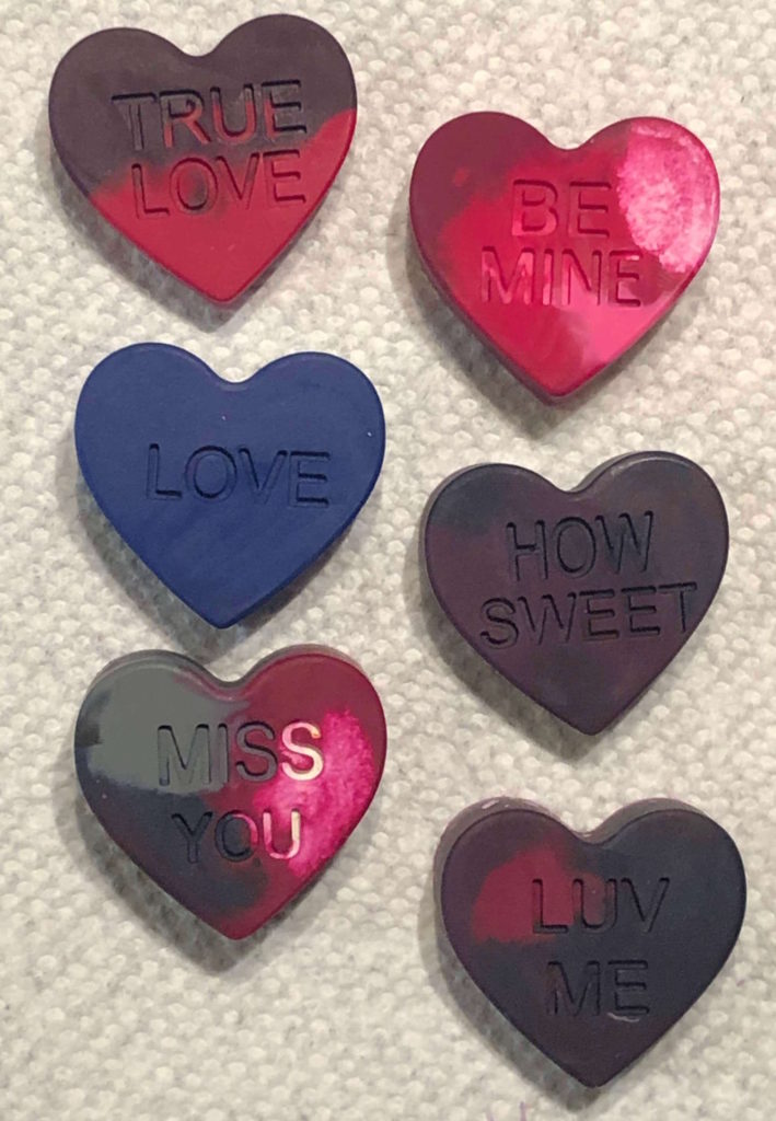 crayon hearts that say "true love," "be mine," "love," "how sweet," "miss you," and "luv me" cool on a paper towel