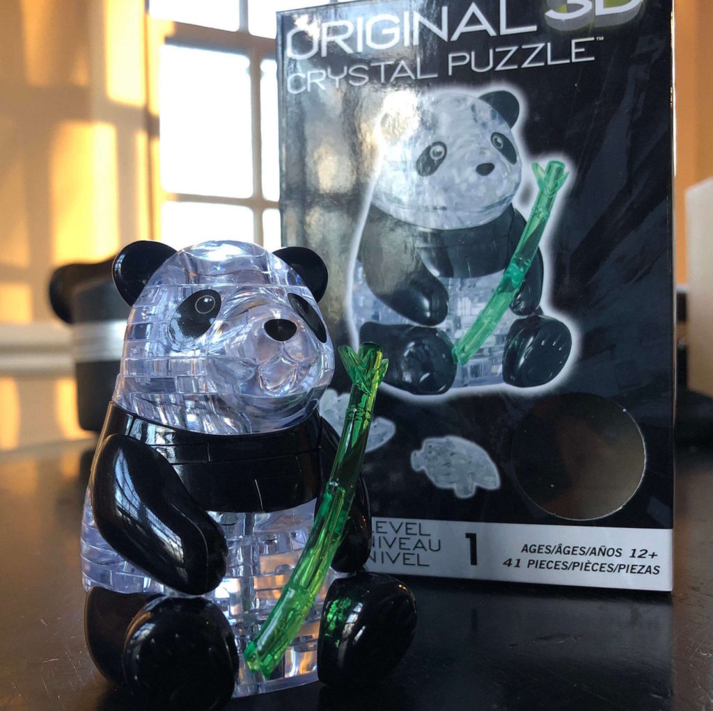 a finished crystal puzzle of a panda with bamboo sits in front of the box with its image on it