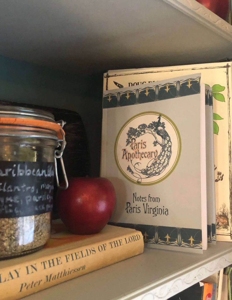 a bookshelf bears an apple, spice blends, and a book that reads "Notes from Paris, Virginia"