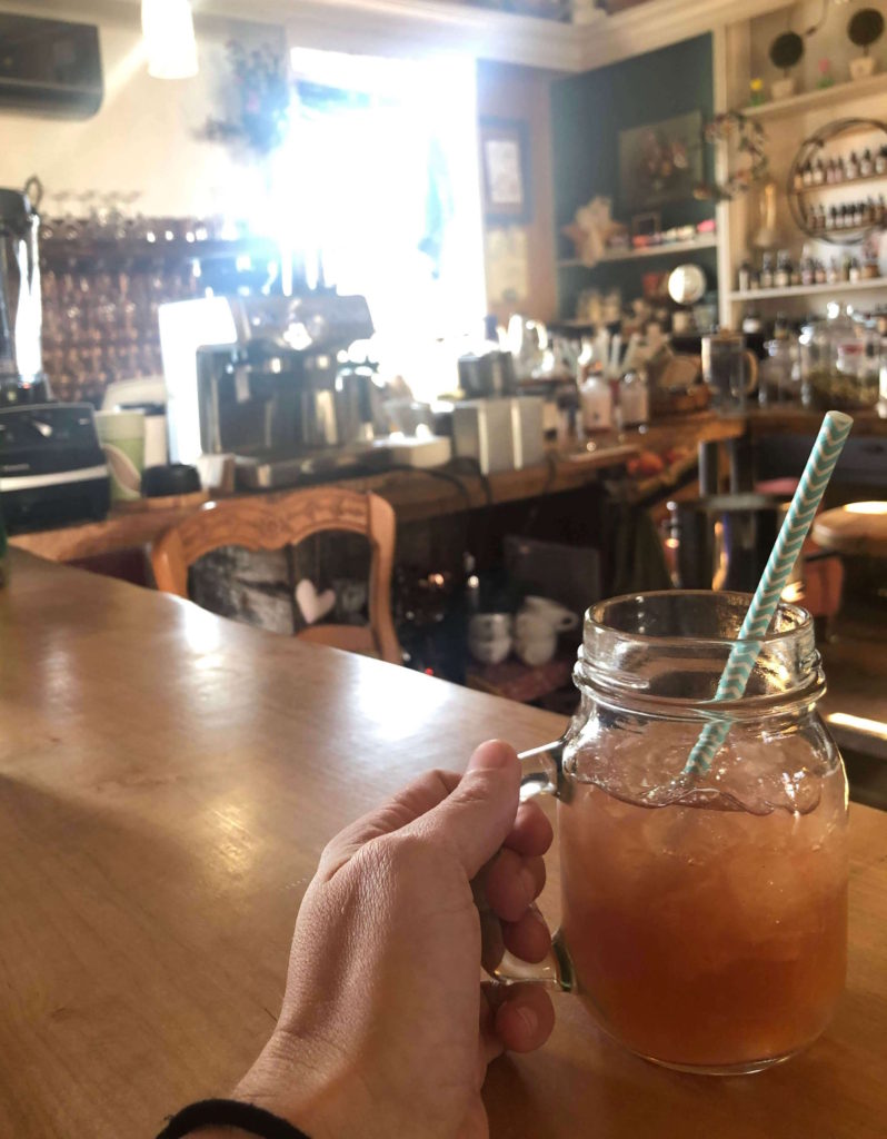 a drink in a mason jar with a paper straw rests on the apothecary bar