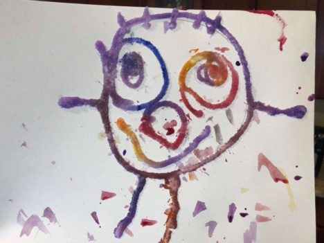 a child's drawing in glue covered in salt after watercolors have been applied and the colors begin to spread