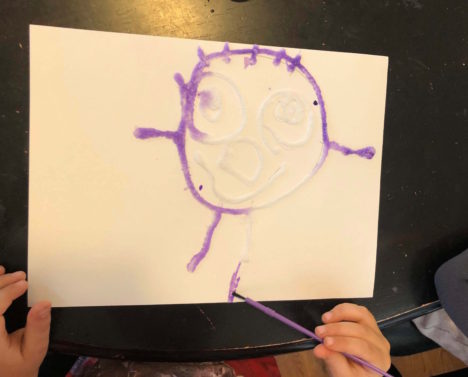 a child's drawing in glue covered in salt, before watercolor paints are applied