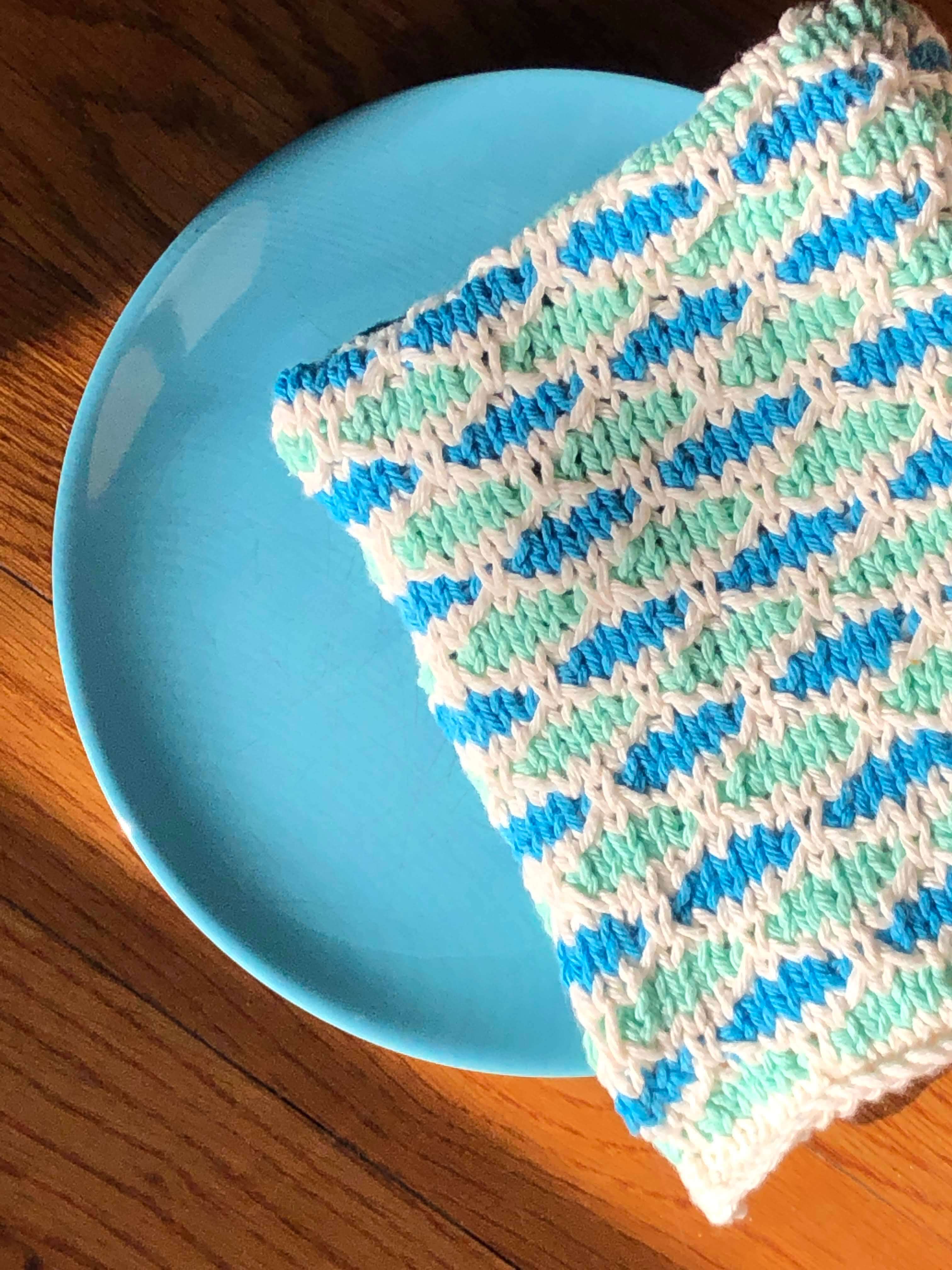 a neatly folded sea spray tea towel rests atop a matching plate on a wooden table