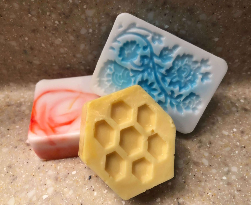 three bars of soap -- honeycomb, swirl, and flower -- rest on granite