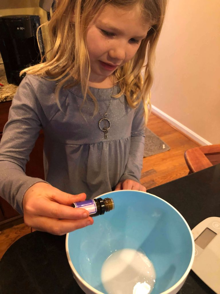 a young girl uses essential oils to scent her soap bars
