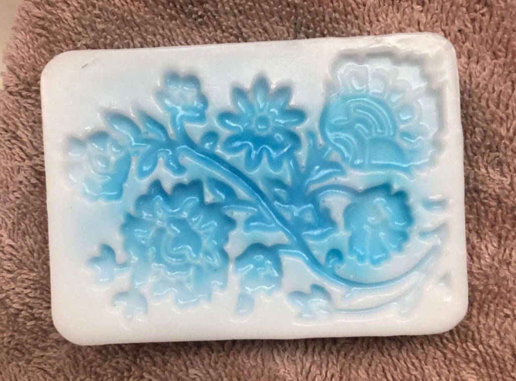 a bar of soap with an embellished flower pattern rests on a towel
